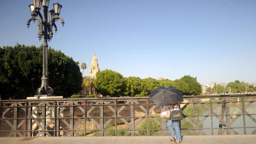 Una ciudadana se protege del sol mientras camina junto al río en Murcia