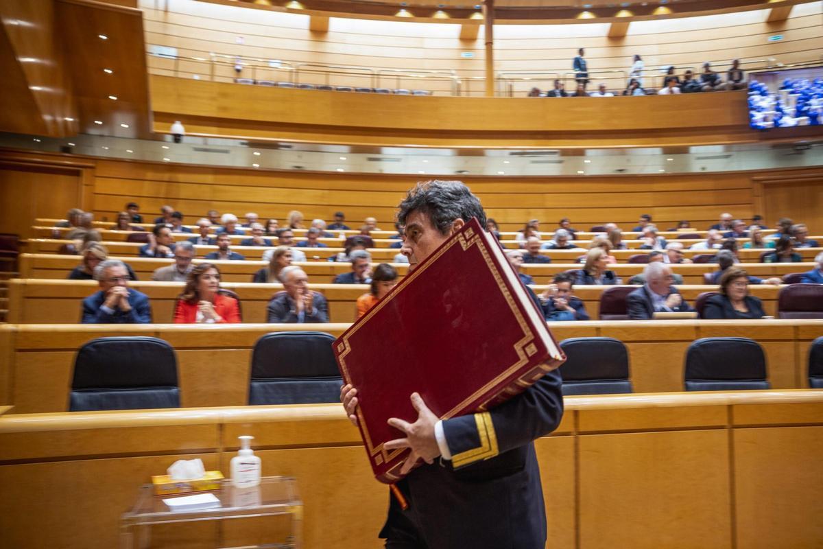 Ujier del Senado retira la Constitución española del salón del pleno después del juramento de un nuevo senador.