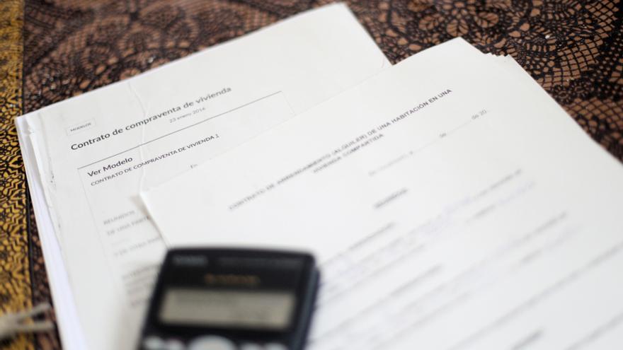 Archivo - Una calculadora sobre un contrato de compraventa de vivienda y un contrato de arrendamiento (alquiler) de una habitación en una vivienda compartida.