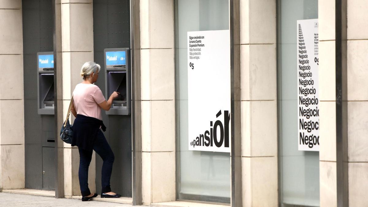 Una mujer realiza una operación bancaria en un cajero situado en el exterior de la entidad, en una imagen de archivo.