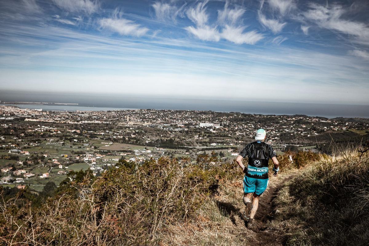 Uno de los participantes, durante el trail, con Gijón al fondo.