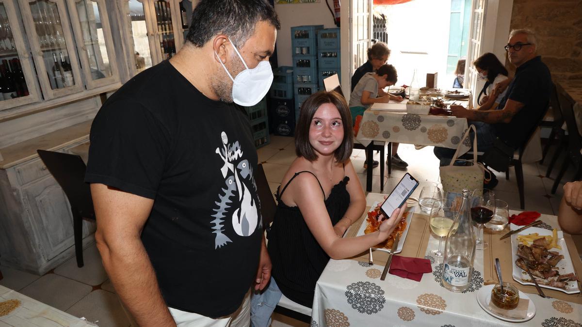 Una clienta muestra su certificado COVID en el interior de un local de Vigo.