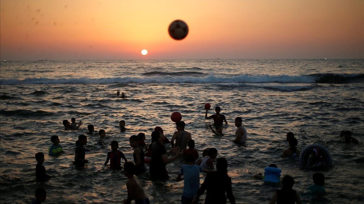 Palestinos juegan con pelotas mientras nadan en el mar Mediterráneo un día caluroso en el norte de la Franja de Gaza