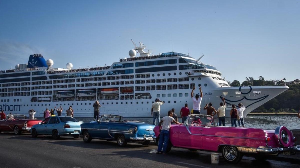 Cubanos montados en automóviles de época saludan la llegada del 'Adonia' a La Habana, este lunes.