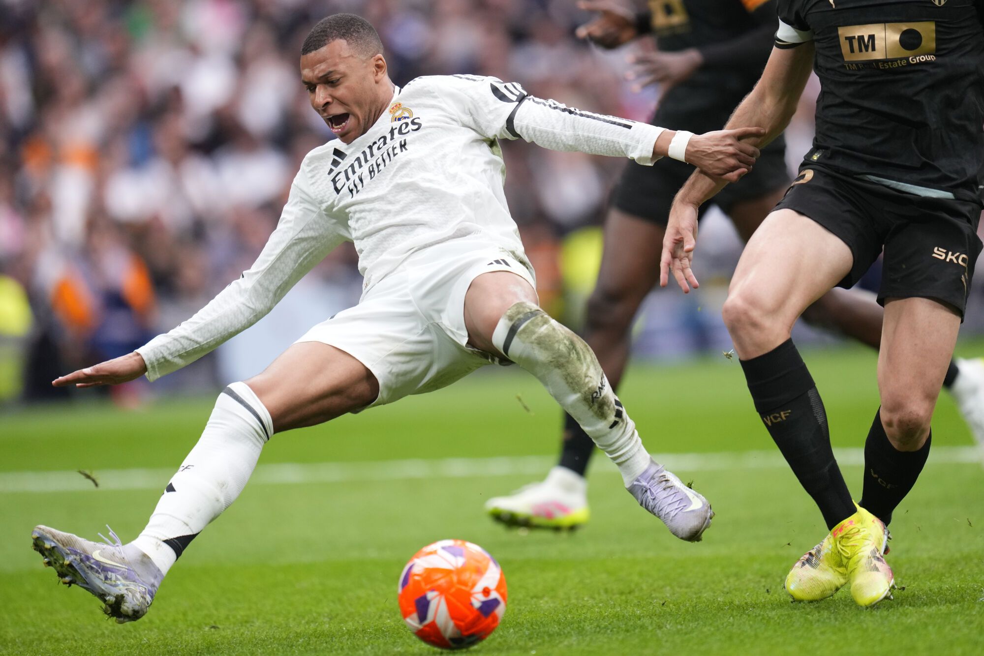 Real Madrid's Kylian Mbappe, left, falls chased by Valencia's Cesar Tarrega during a Spanish La Liga soccer match between Real Madrid and Valencia at the Santiago Bernabeu stadium in Madrid, Spain, Saturday, April 5, 2025. (AP Photo/Manu Fernandez)