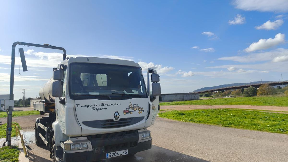 Un camión cisterna se abastece de agua en un surtidor.