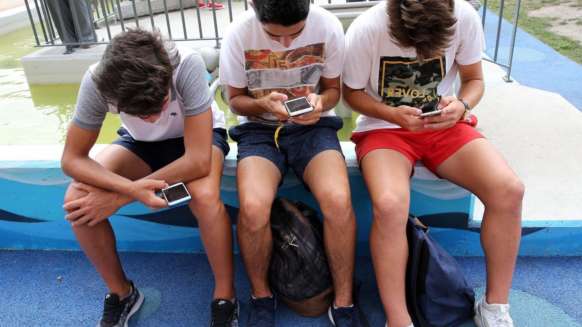 Tres jóvenes usando el teléfono móvil.