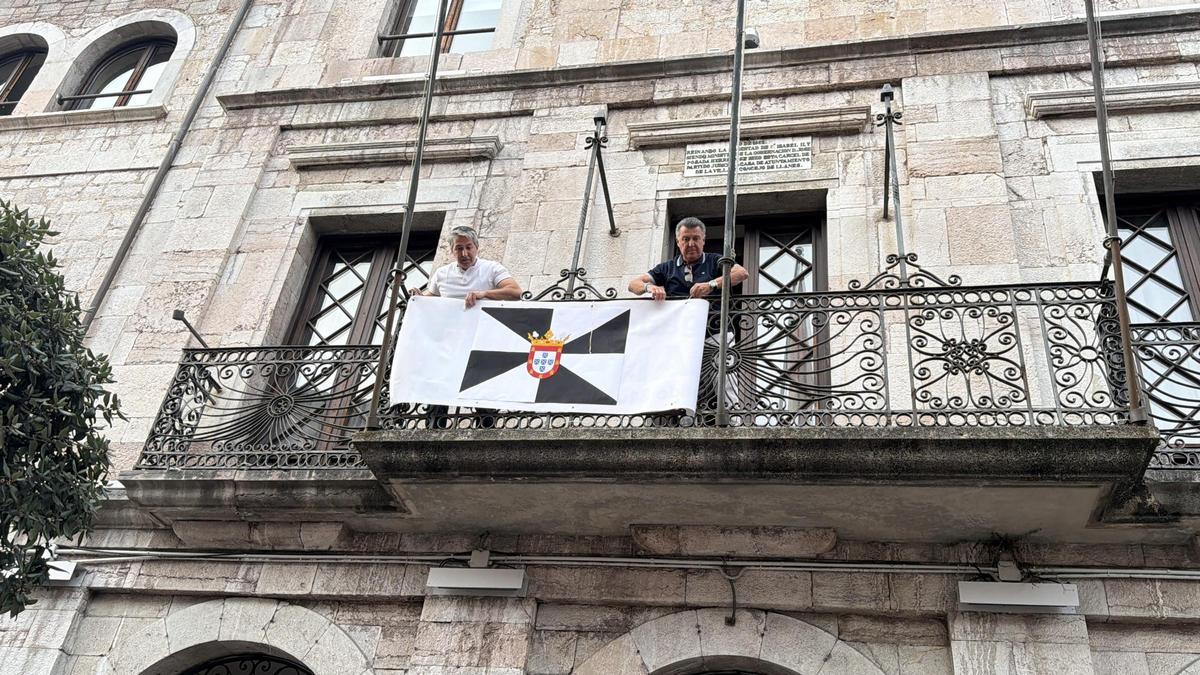 Los concejales del PP de Llanes Josín Amor –izquierda– y Juan Carlos Armas colocal una bandera de Ceuta en el balcón del Ayuntamiento.
