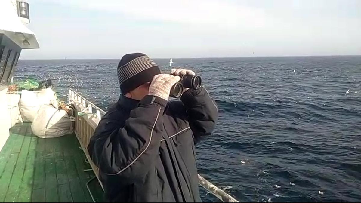 Un tripulante de uno de los barcos buscando en el mar, ayer.