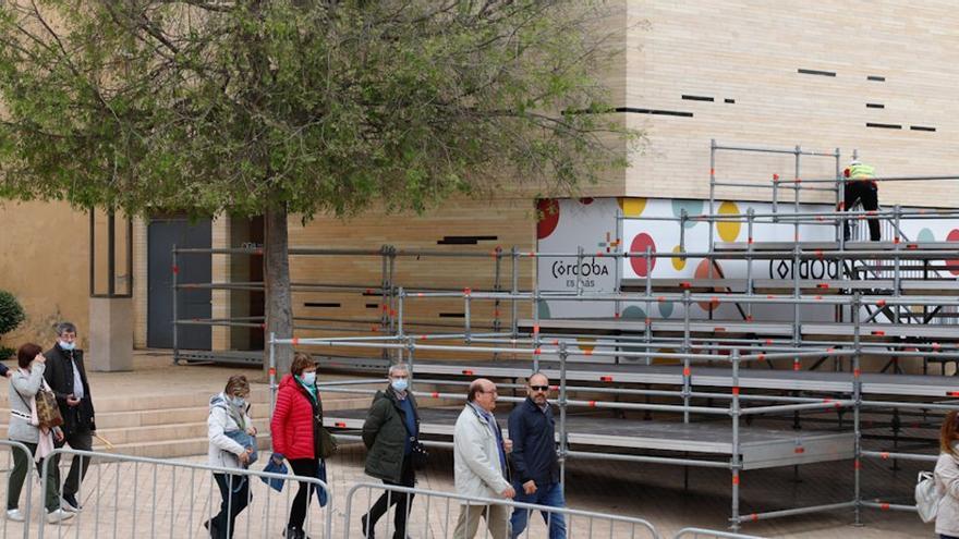 Turistas pasean por la Puerta del Puente durante el montaje de los palcos de la carrera oficial de la Semana Santa.