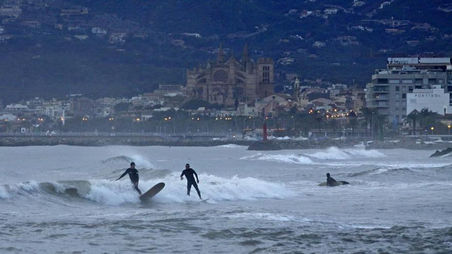 Aficionados practicando surf en la playa de Ciudad Jardín aprovechando un temporal de viento.