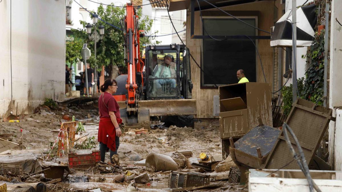 Los vecinos de Benamargosa se afanan en limpiar sus calles tras el desbordamiento del río.