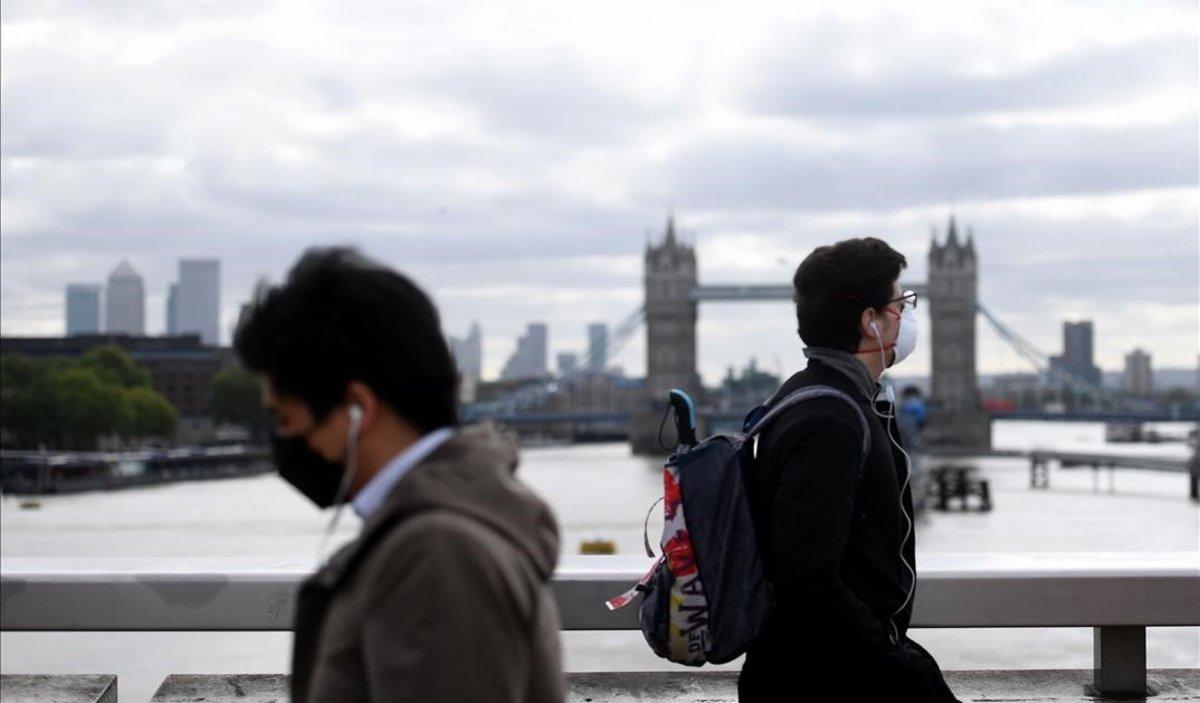 Ciudadanos con máscara pasan por el puente de Londres.