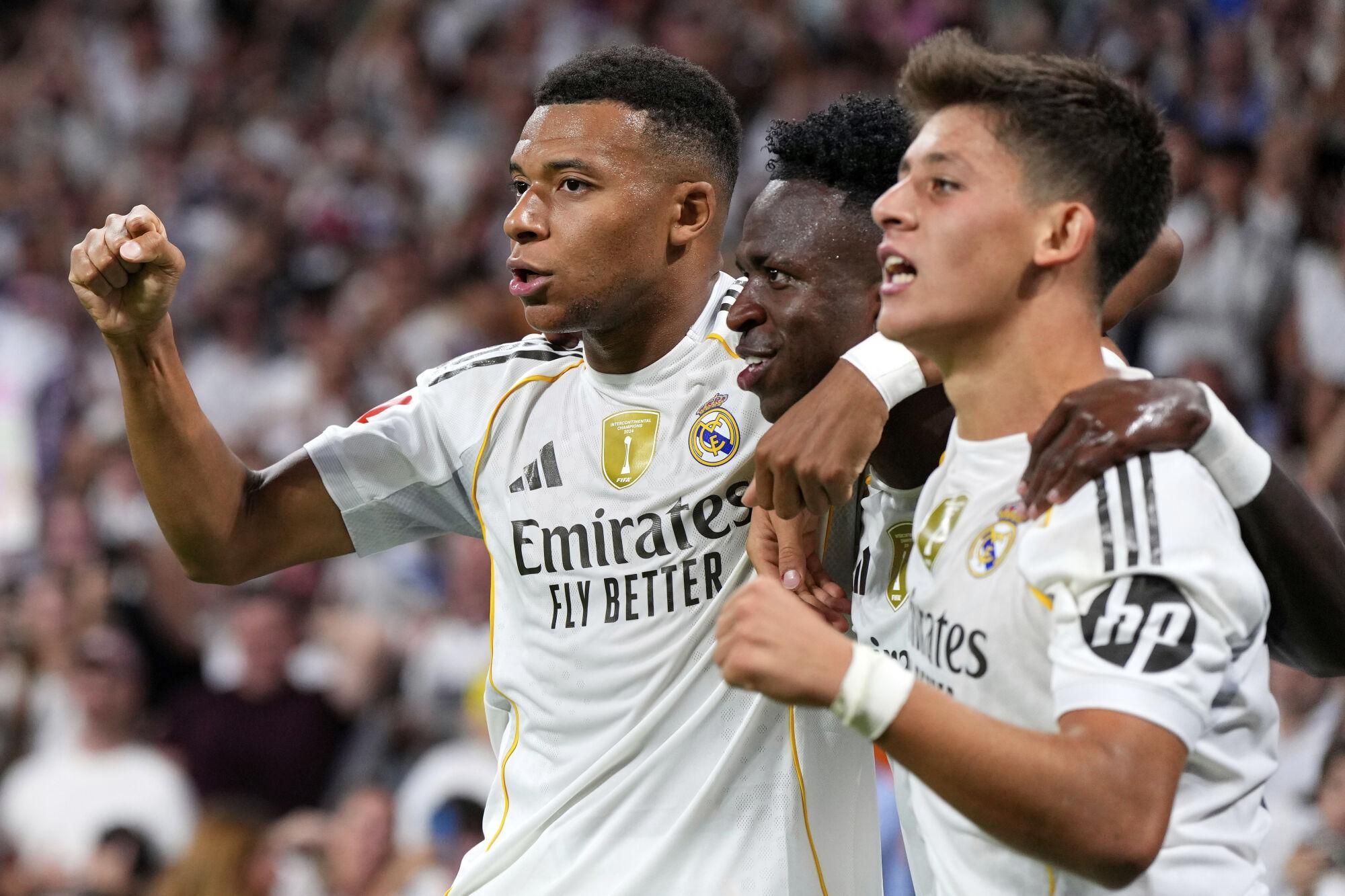 Real Madrid's Vinicius Junior, center, celebrates with Arda Guler, right, and Kylian Mbappe after scoring his side's second goal during the Spanish La Liga soccer match between Real Madrid and Mallorca in Madrid, Saturday, Aug. 30, 2025. (AP Photo/Manu Fernandez)