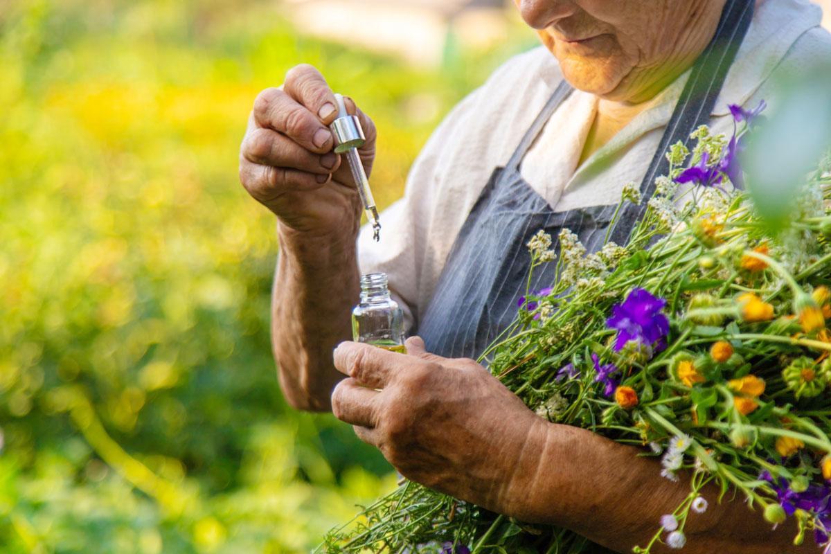 Una mujer de avanzada edad maneja un frasco de una flor de Bach.