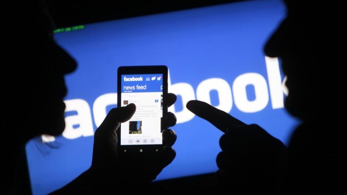 Dos usuarios de 'smartphones' muestran sus aplicaciones de Facebook.