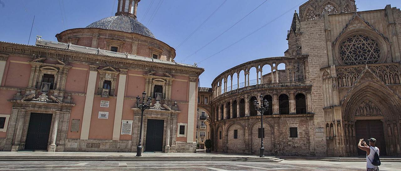 Un turista fotografía una plaza de la Virgen de València desierta por la pandemia, el pasado mes de julio. | LEVANTE-EMV