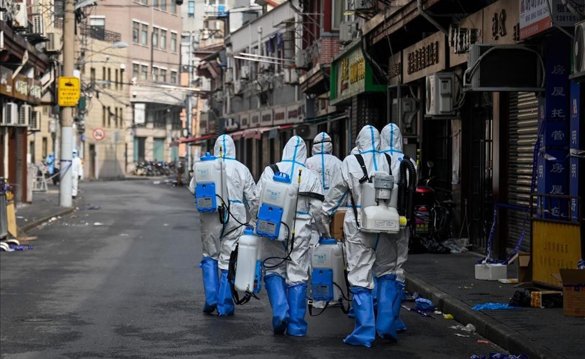 TOPSHOT - Health workers in protective gear prepare to spray disinfectant in a blocked off area in Shanghai s Huangpu district on January 27  2021  after residents were evacuated following the detection of a few cases of COVID-19 coronavirus in the neighbourhood  (Photo by STR   AFP)   China OUT