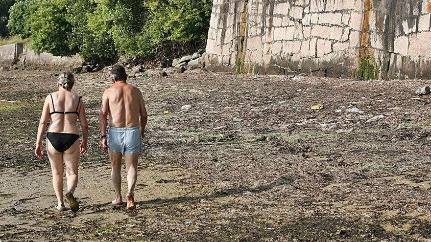 Dos bañistas caminan por la zona intermareal de Cesantes.