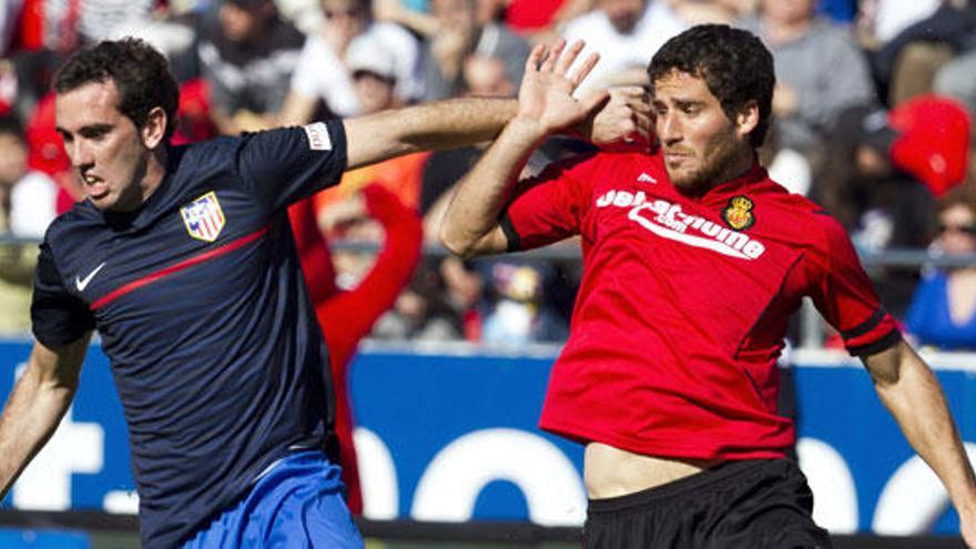 El defensa del Atlético de Madrid Diego Godín (i) pugna por el balón con el delantero israelí del RCD Mallorca Tomer Hemed durante el partido, correspondiente a la vigésimo octava jornada de Liga de Primera División, que disputan ambos equipos esta tarde en el estadio Iberostar.