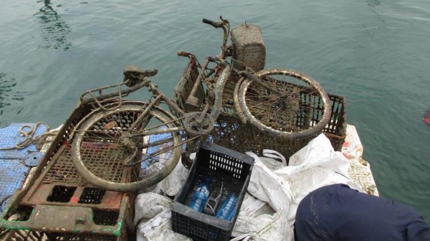 En primer plano, una de las bicicletas retiradas del fondo del Puerto junto a todo tipo de basura.