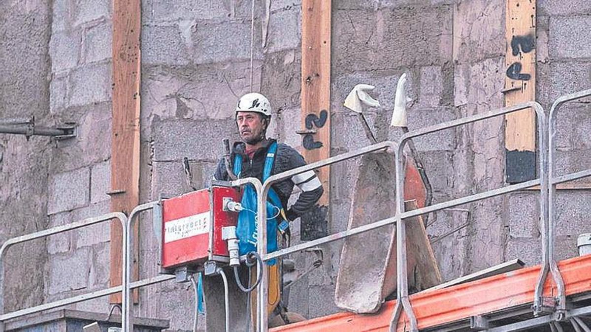 Un obrero trabaja desde el andamio en un futuro edificio de viviendas.