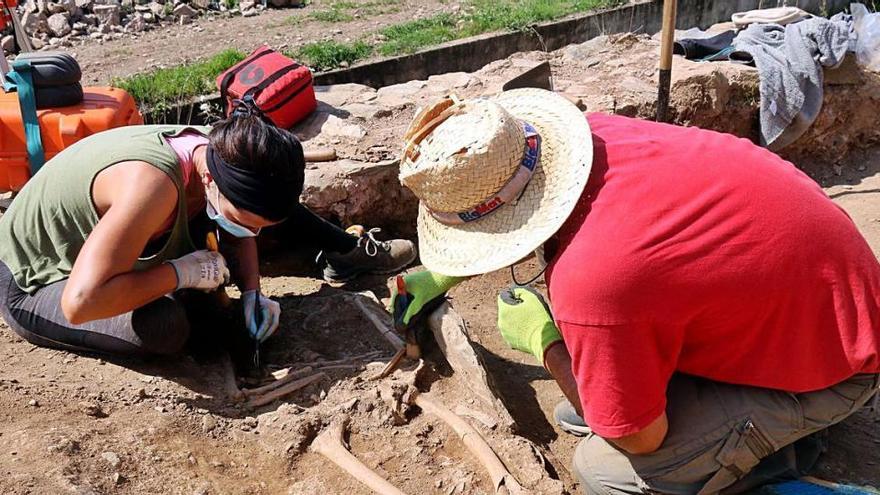 Dos dels arqueòlegs netejant un dels esquelets medievals trobats a Sant Julià de Ramis.