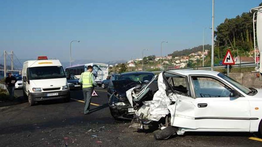 En primer término los dos coches accidentados, y al fondo, el autobús que embistió al turismo.