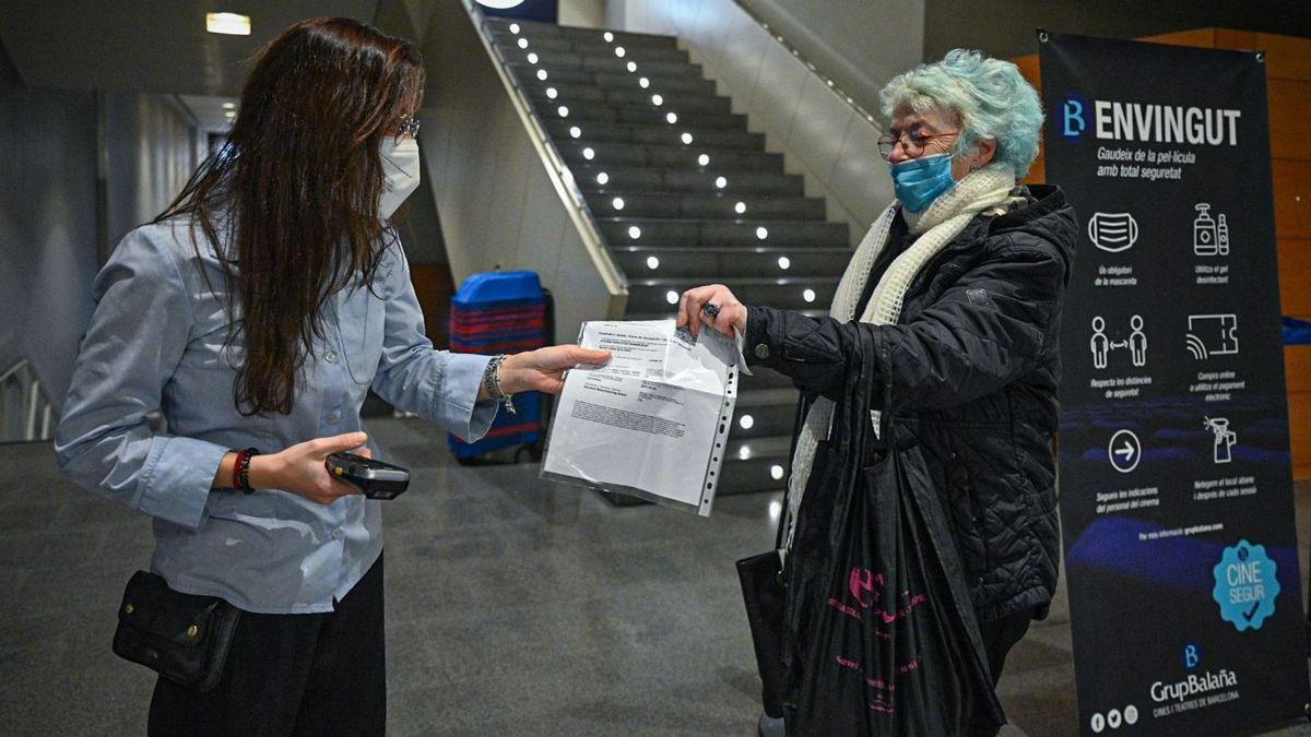 Una señora enseña el pasaporte covid en la entrada de los multicines Bosque.