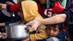 Niños palestinos esperan para recibir comida en una cocina benéfica, en Rafah, Gaza | M. SALEM / REUTERS