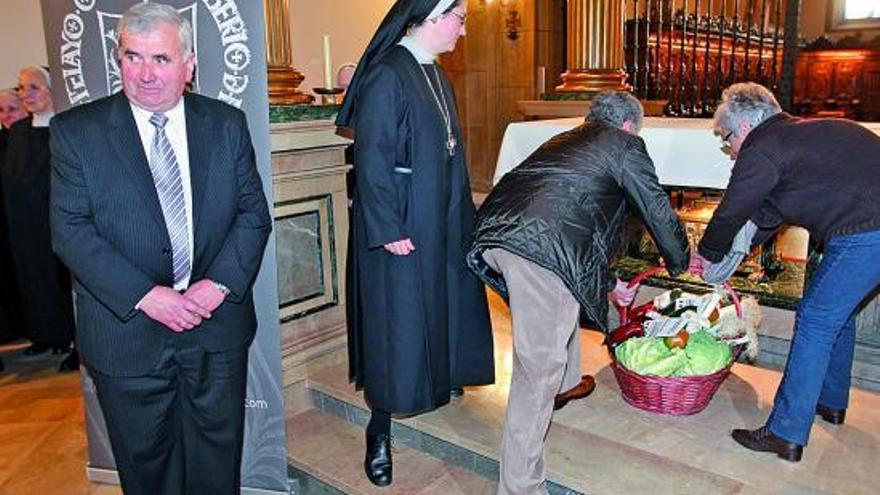 Dos vecinos de Sariego depositan una cesta con productos de la huerta en el altar de la iglesia de las Pelayas ante la mirada de la abadesa sor Rosario del Camino y junto al alcalde del municipio saregano, Javier Parajón.