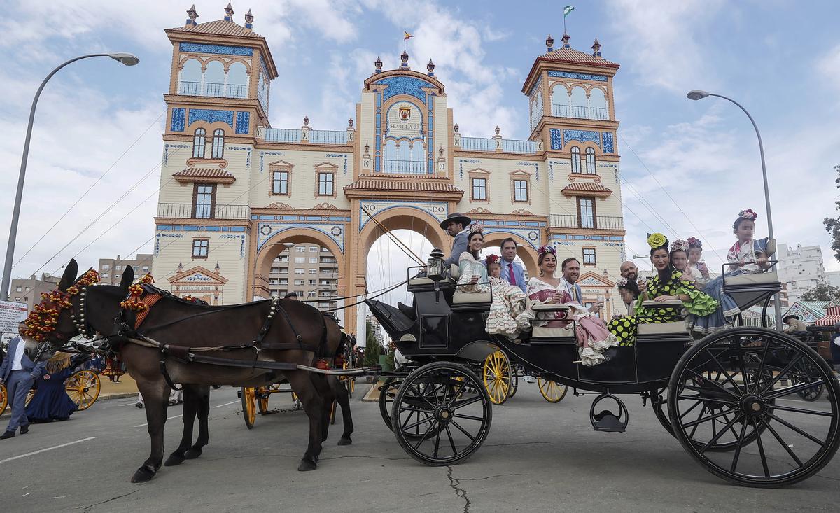 Una familia en un carruaje se fotografía, este miércoles, frente a la portada de la Feria de Abril de Sevilla.