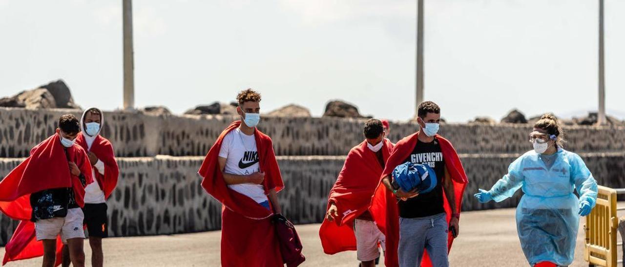 Una voluntaria de Cruz Roja atiende a dos migrantes en su llegada a Lanzarote.