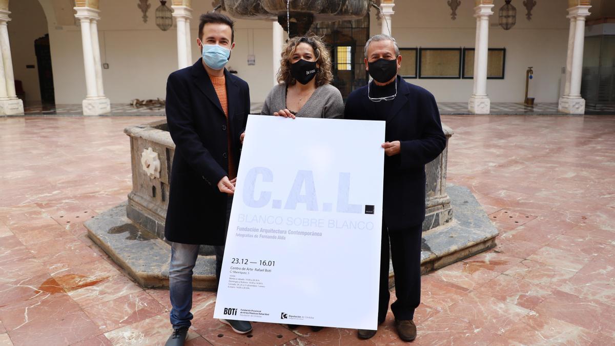 Salud Navajas sostiene el cartel de la exposición junto a dos de los responsables de la muestra.