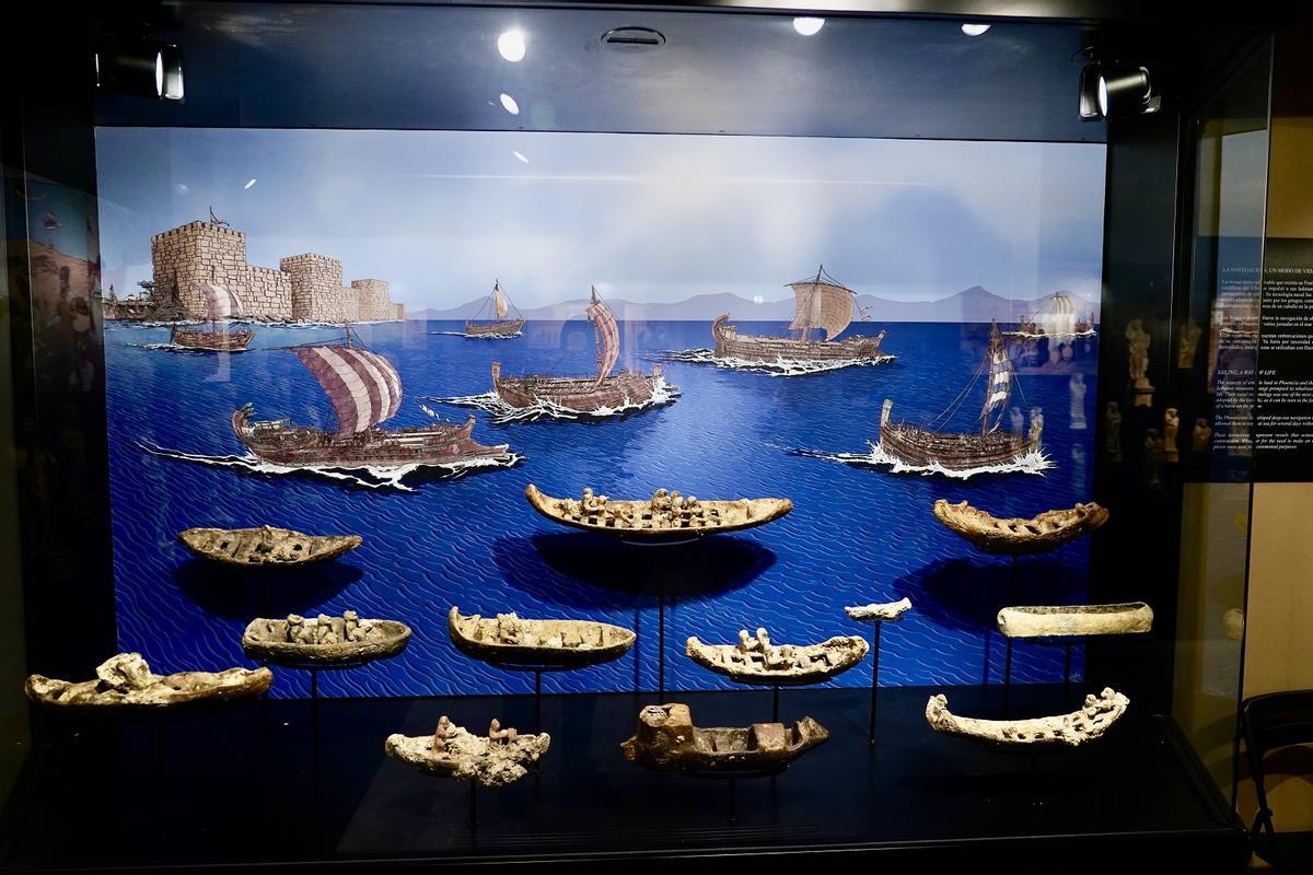 Figuras de terracota de embarcaciones, con la ilustración de fondo de Julio Antonio Valero.
