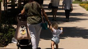 Una mujer pasea con su hijo y un cochecito de bebé, en Madrid.