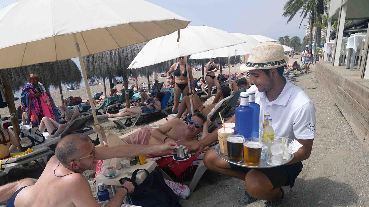Un trabajador de un chiringuito de Málaga atiende a los clientes a pie de playa.