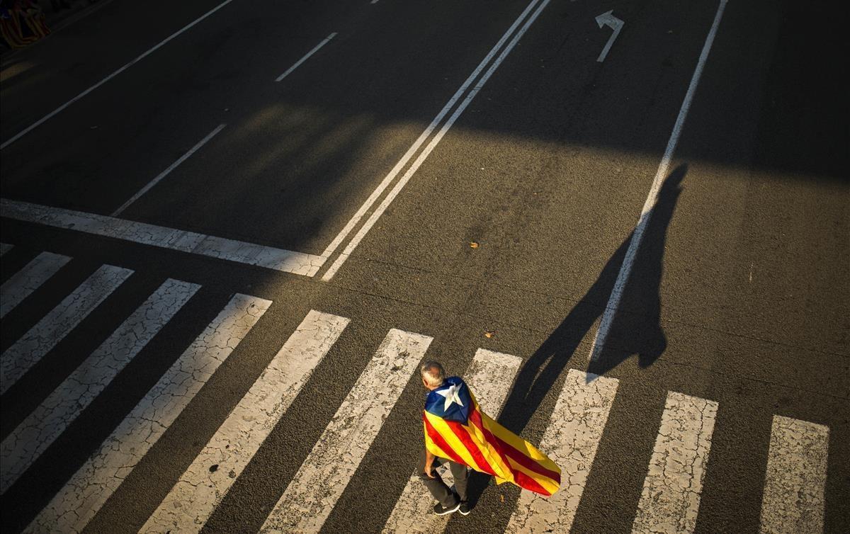 Un hombre camina con su ’estelada’ antes del cierre de campaña en Barcelona.