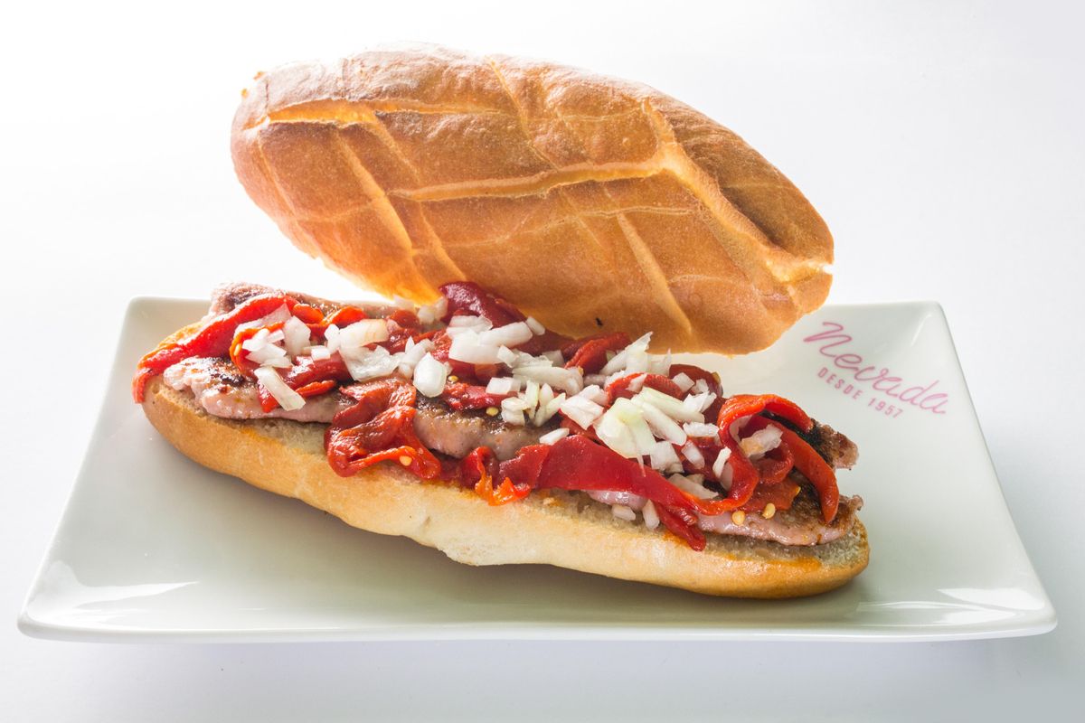 Exquisito bocadillo de salchicha fresca del país, pimiento del piquillo y cebolla.