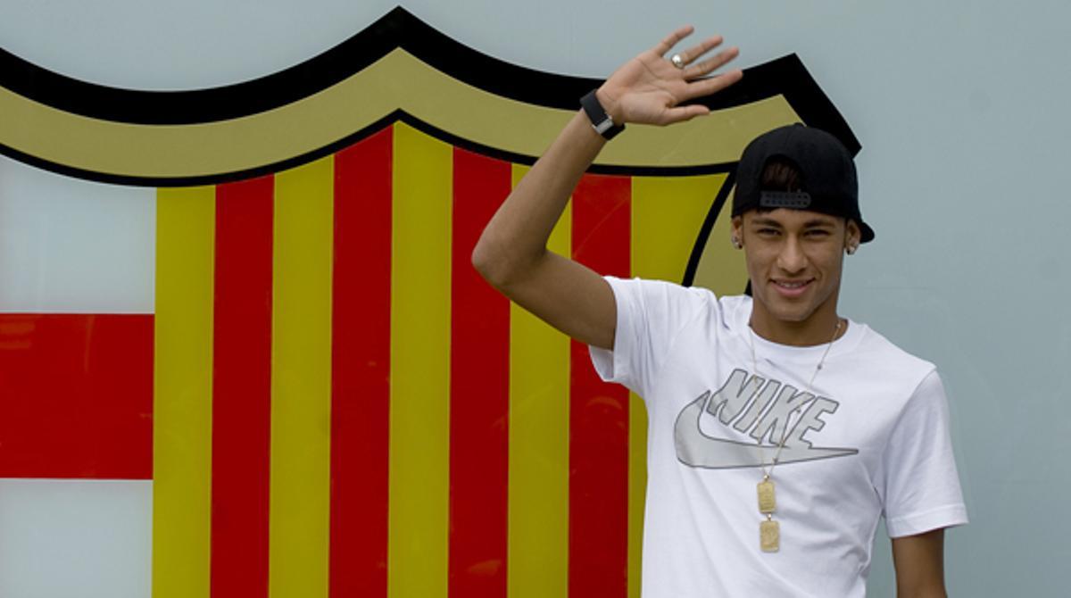 Neymar posa per als mitjans de comunicació davant de l’escut blaugrana, a l’entrada principal de les oficines del Barça.