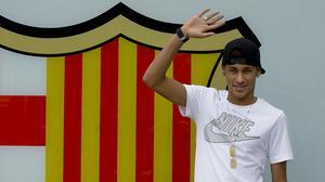 Neymar posa per als mitjans de comunicació davant de l’escut blaugrana, a l’entrada principal de les oficines del Barça.