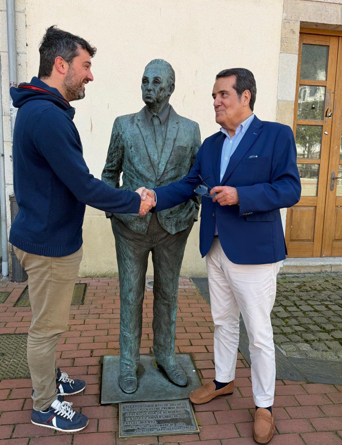 Óscar Pérez y Julián Moreno sellando el acuerdo ante la estatua de Severo Ochoa, en Luarca.