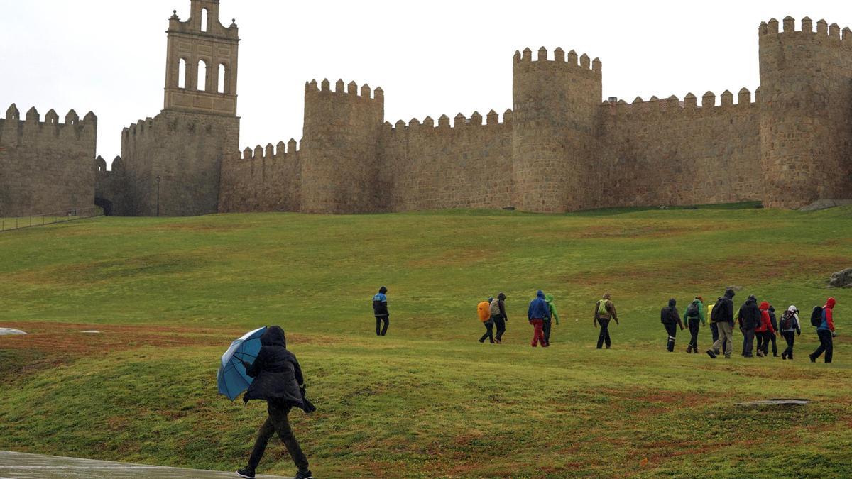 Varias personas pasean cerca de la muralla de Ávila.