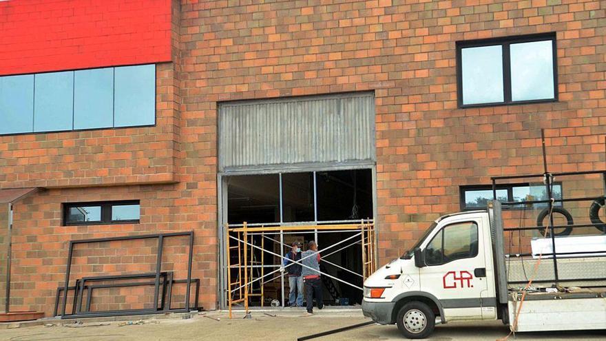 Dos operarios trabajan en el portalón de la nave, horas después del accidente laboral.