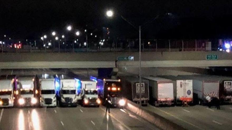 Varios camiones alineados en la autopista bajo un puente impiden un suicidio