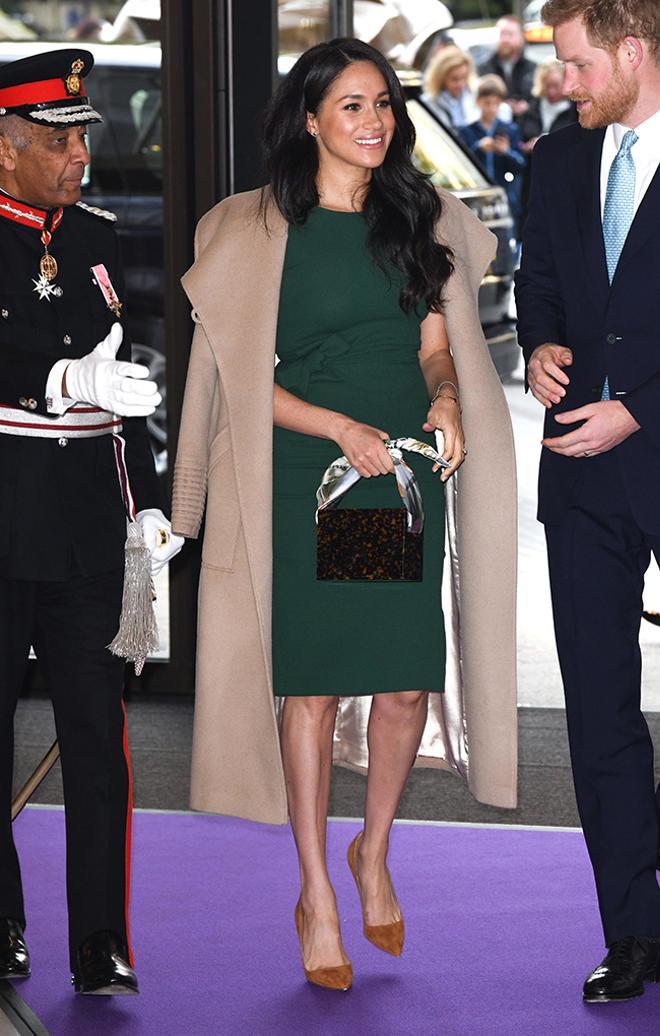 Meghan Markle con vestido verde y abrigo sobre los hombros