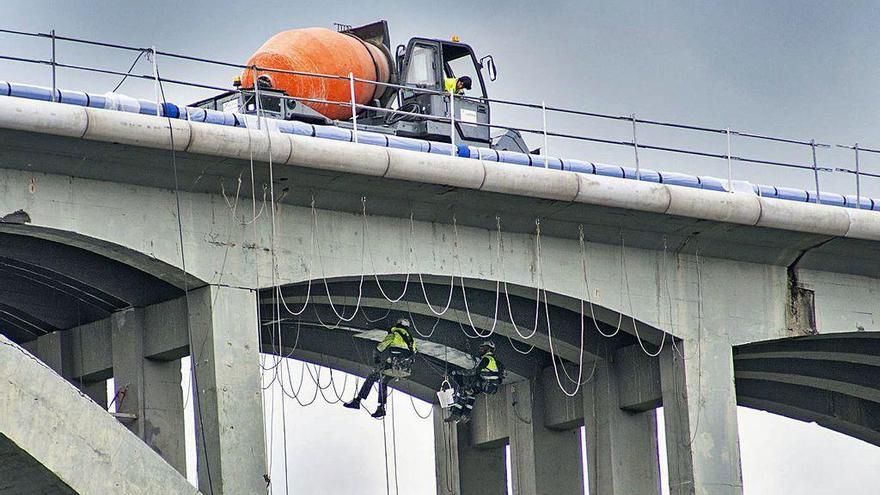 Operarios trabajando en el viaducto, con anclajes y cuerdas de seguridad.