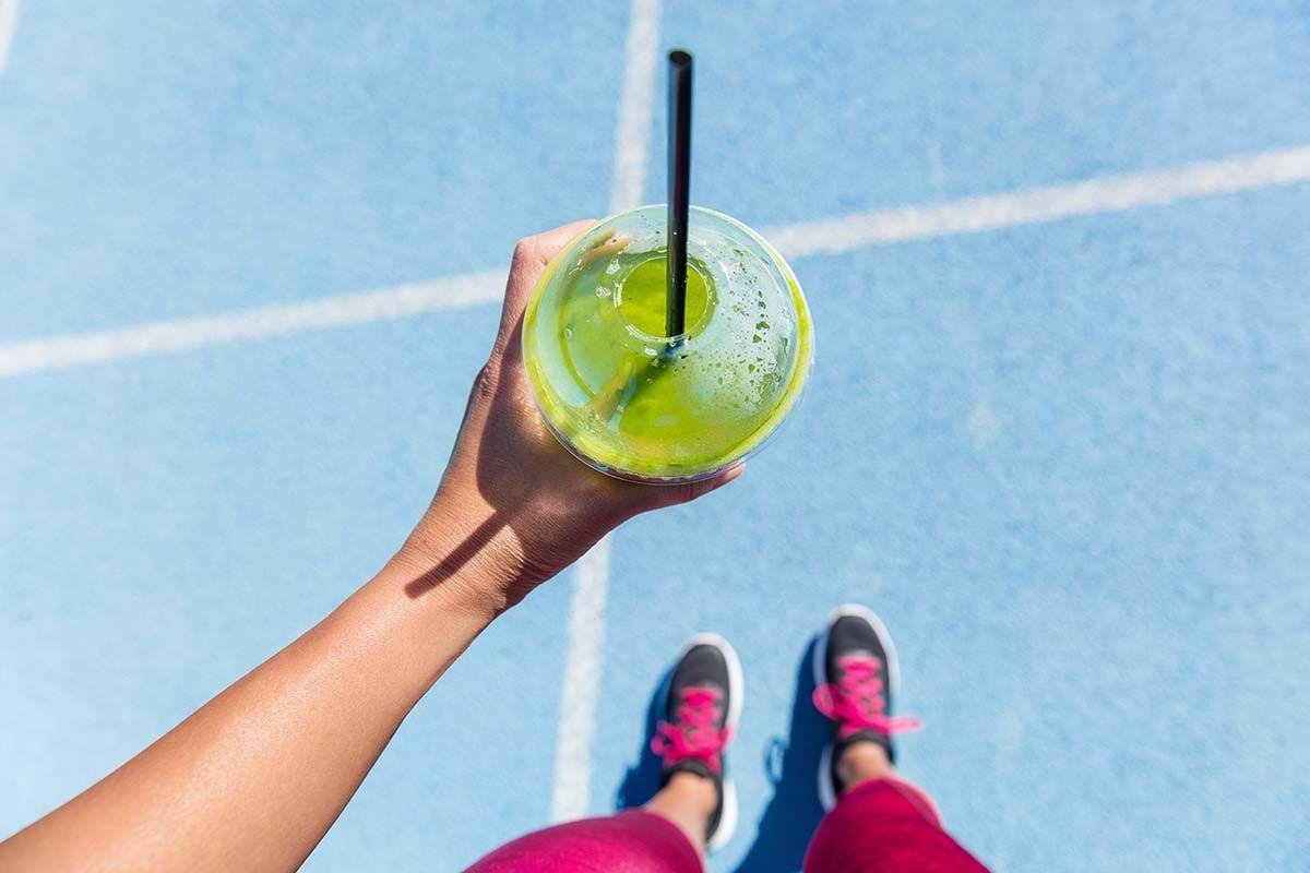 Una corredora runner bebe un líquido verde batido detox clorofila
