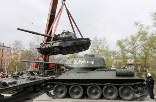 Workers install a demilitarized Soviet-made T-62M1 tank near a Soviet World War Two T-34 tank at a memorial in a park in Krasnoyarsk
