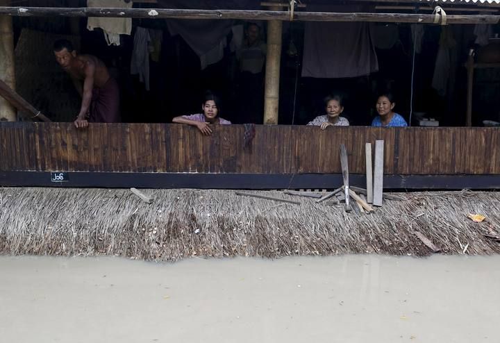 People sit at their home in a flooded village outside Zalun Township, Irrawaddy Delta